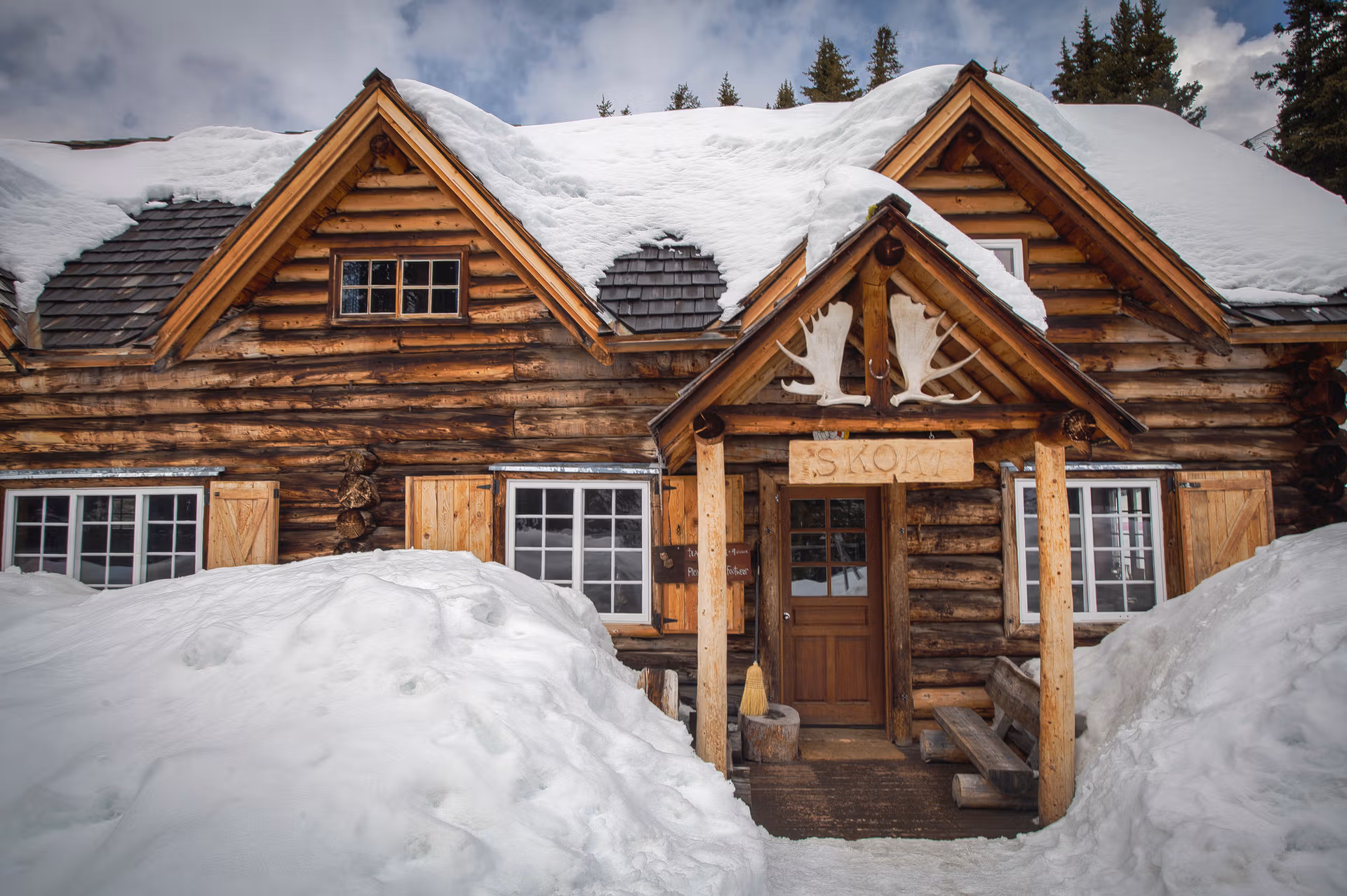 Snow-covered log lodge in a high mountain valley